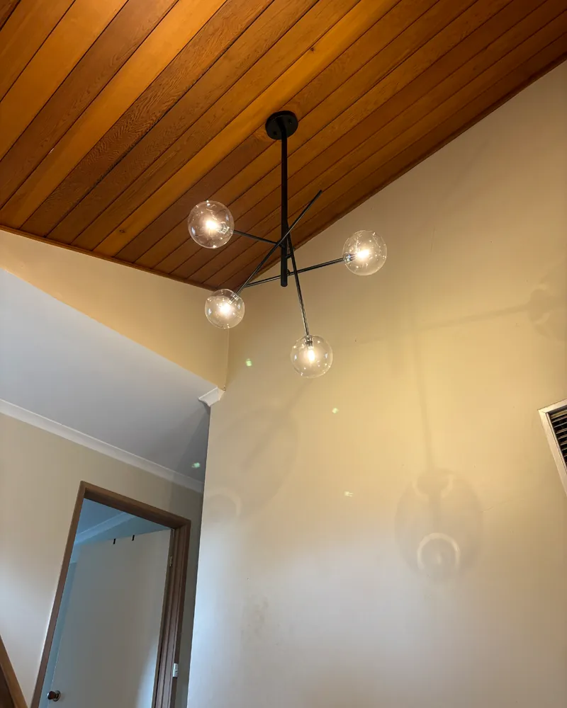 Multi-arm chandelier beneath a timber ceiling installed by Espire Electrical