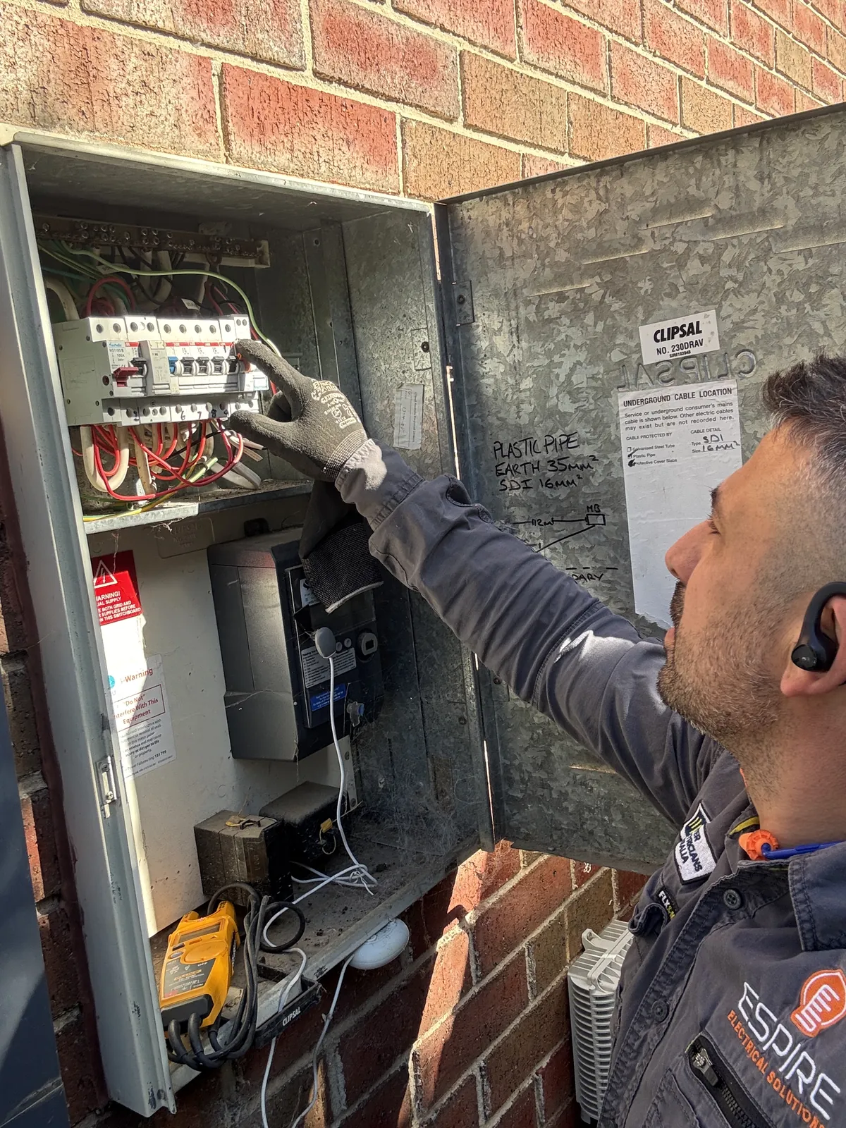Espire Electrical electrician checking circuit breakers in an outdoor switchboard