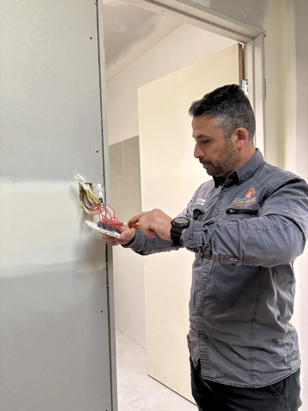 Espire Electrical electrician connecting a wall outlet in a home