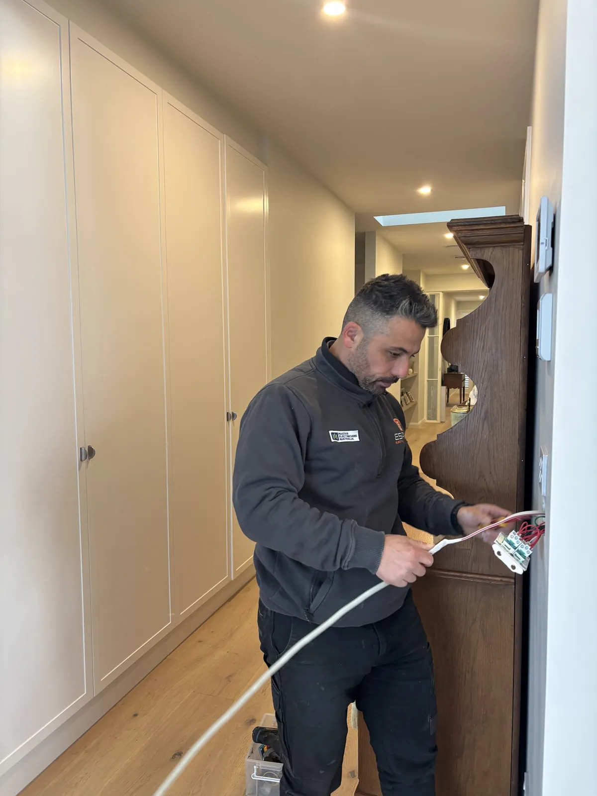Mardi from Espire Electrical wiring an electrical outlet in a home hallway