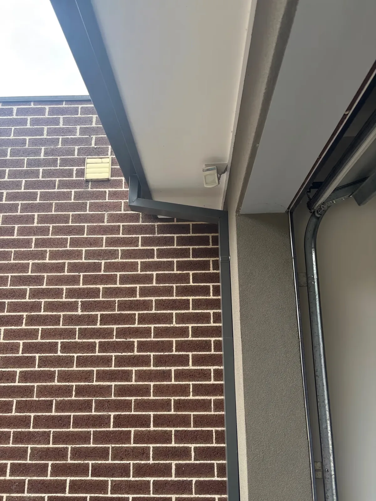 Outdoor air-conditioning unit beside a brick wall serviced by Espire Electrical